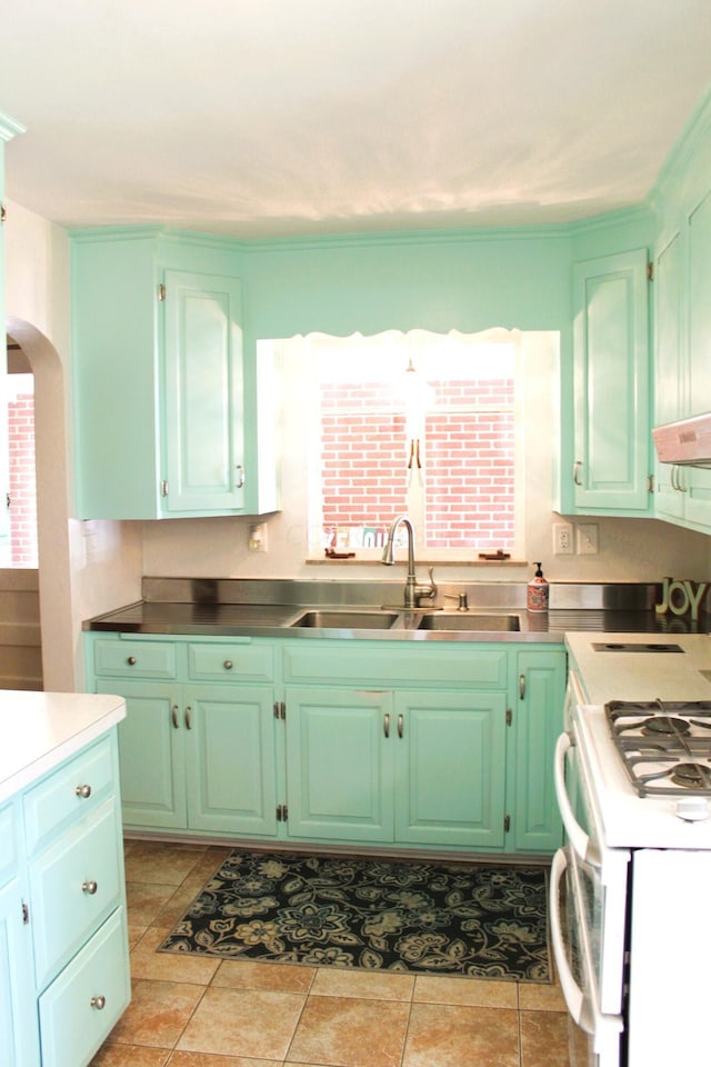 kitchen with white gas range, sink, light tile patterned floors, and plenty of natural light