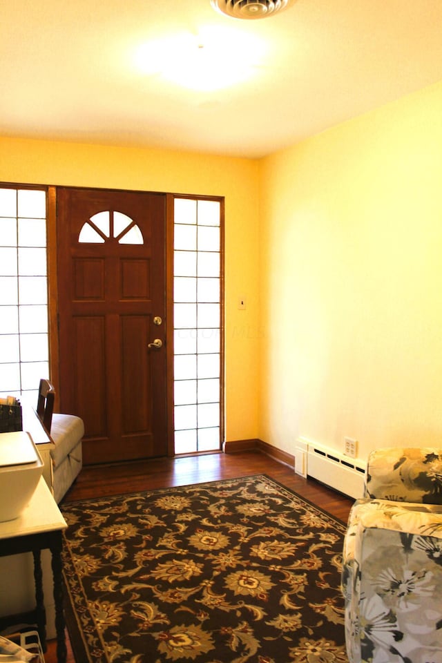 foyer with dark wood-type flooring and a baseboard heating unit