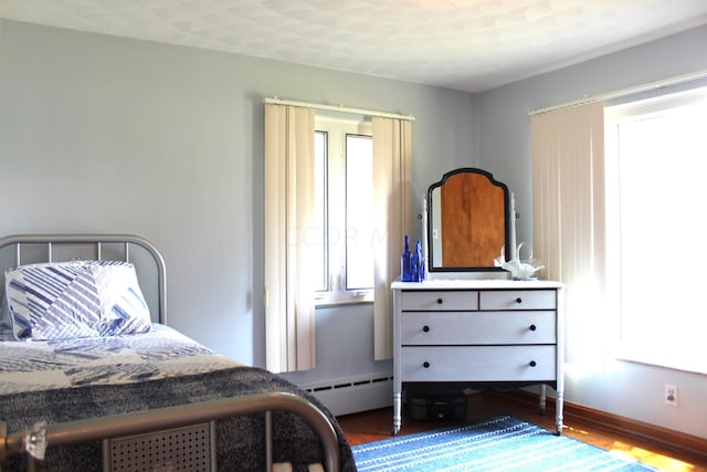 bedroom with a textured ceiling, dark hardwood / wood-style flooring, and baseboard heating