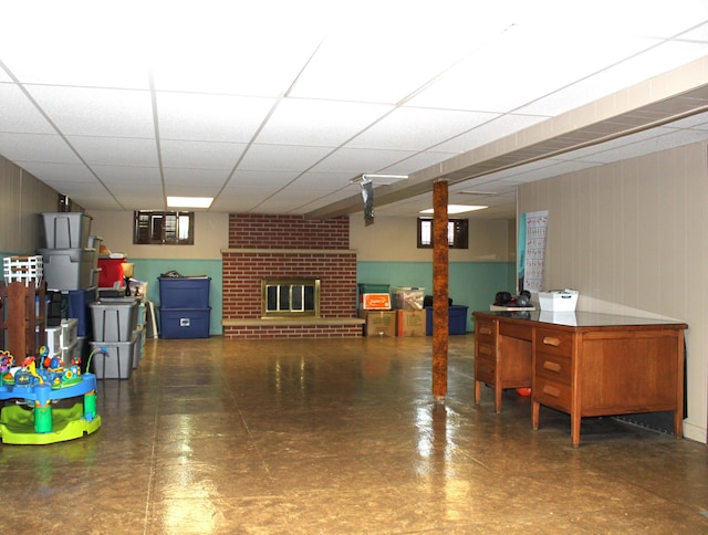 interior space with a paneled ceiling and a brick fireplace