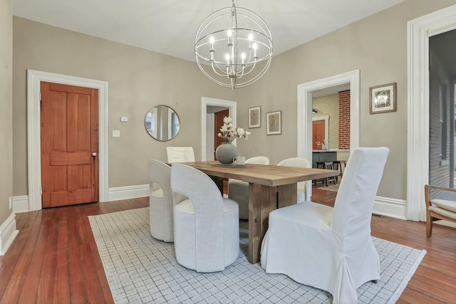 dining space featuring wood-type flooring and an inviting chandelier