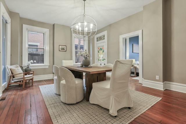 dining room with wood-type flooring, a healthy amount of sunlight, and a notable chandelier