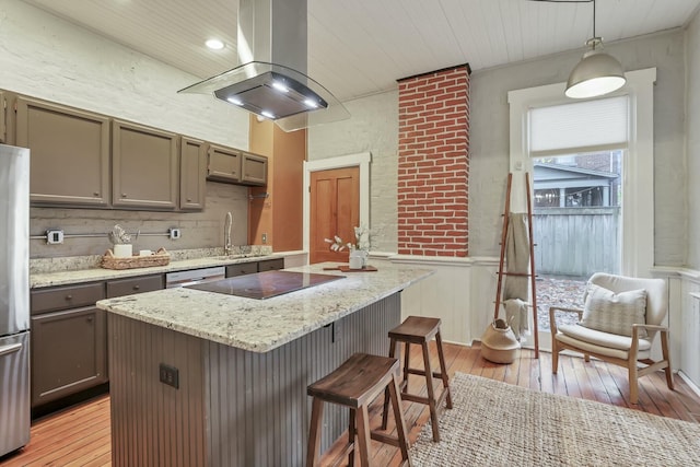 kitchen featuring a center island, decorative light fixtures, light hardwood / wood-style floors, and island exhaust hood