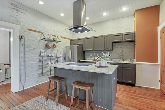 kitchen with island exhaust hood, gray cabinets, light hardwood / wood-style flooring, and stainless steel refrigerator