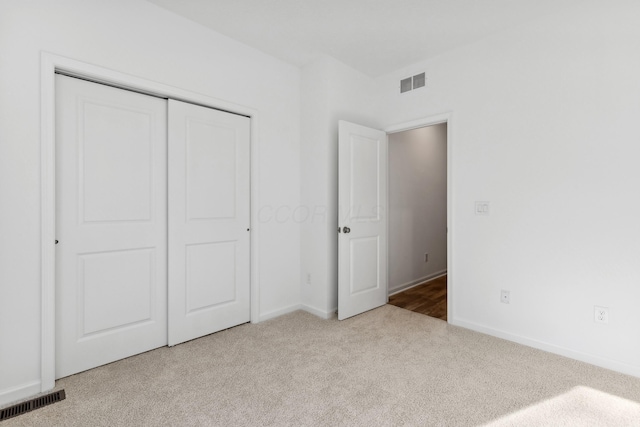 unfurnished bedroom featuring light carpet and a closet