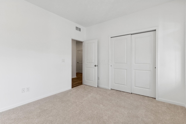 unfurnished bedroom featuring light carpet and a closet