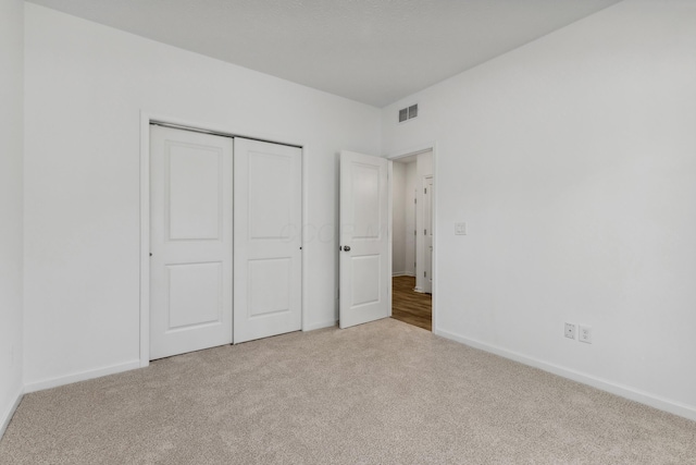 unfurnished bedroom featuring a closet and light colored carpet