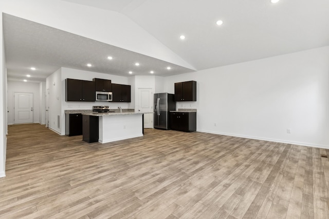 kitchen with a center island with sink, light stone counters, light wood-type flooring, and stainless steel appliances