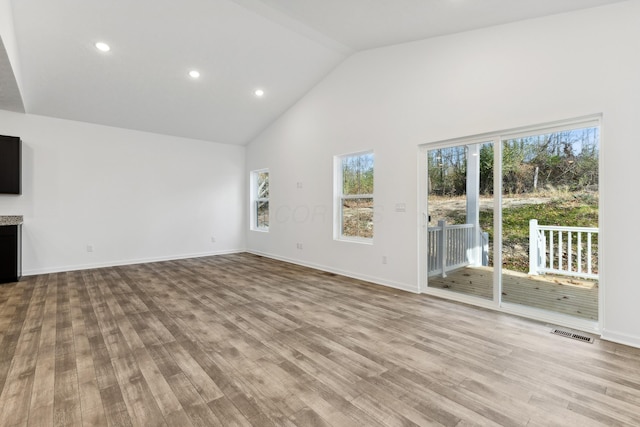 unfurnished living room featuring high vaulted ceiling and light hardwood / wood-style floors