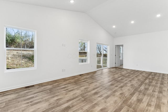 spare room with light hardwood / wood-style floors and high vaulted ceiling