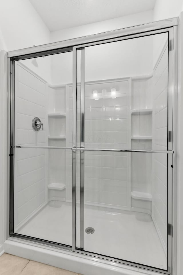 bathroom with tile patterned floors and a shower with door