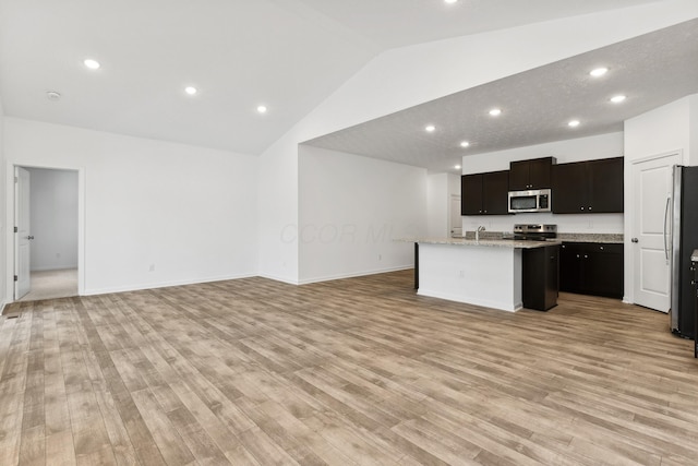 kitchen featuring a center island with sink, light stone counters, light wood-type flooring, and stainless steel appliances