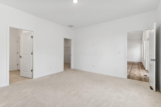 unfurnished bedroom featuring light carpet, a spacious closet, and a closet