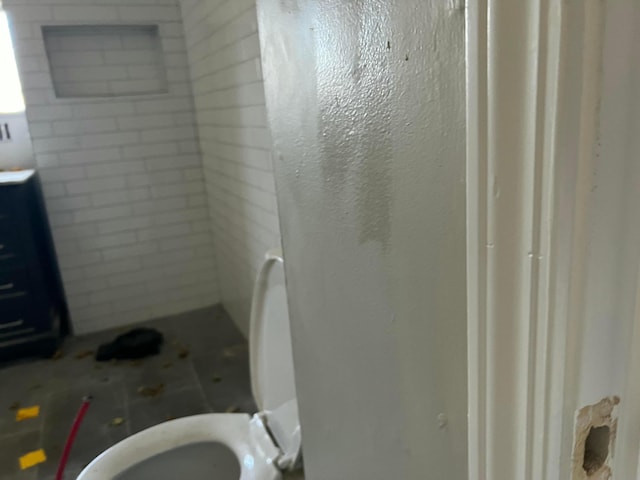 bathroom with a tile shower and toilet