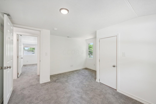 empty room with light colored carpet, vaulted ceiling, and a wealth of natural light