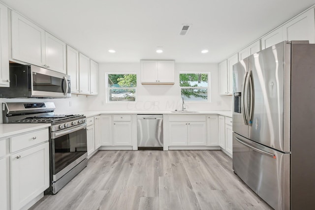 kitchen with white cabinetry, sink, stainless steel appliances, and light hardwood / wood-style floors