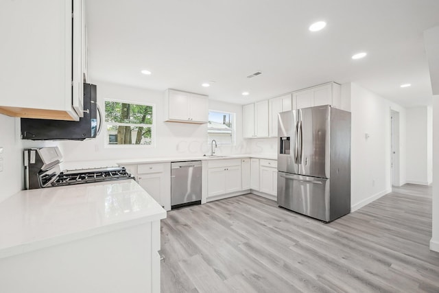 kitchen featuring light wood-type flooring, white cabinetry, and stainless steel appliances