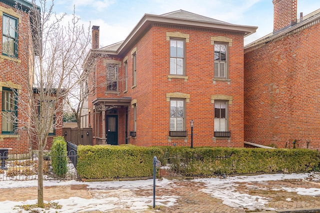 exterior space with a chimney, fence, and brick siding