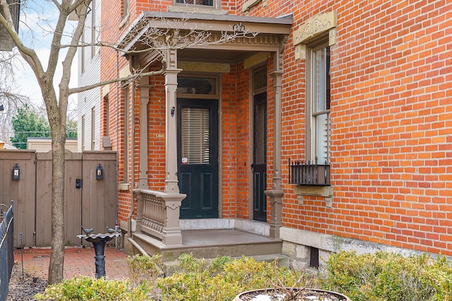 property entrance featuring brick siding and fence