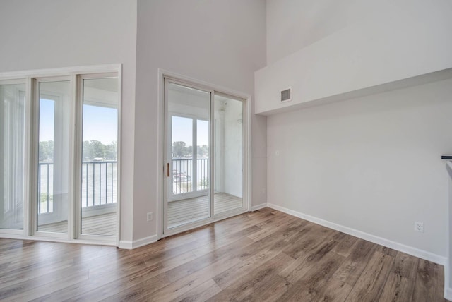 empty room with hardwood / wood-style floors, a healthy amount of sunlight, and a high ceiling