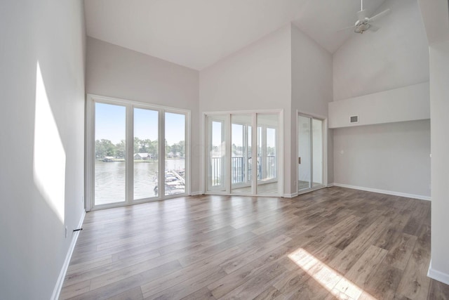 unfurnished room featuring ceiling fan, a water view, light hardwood / wood-style floors, and high vaulted ceiling