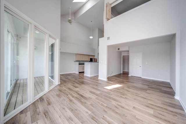 unfurnished living room with ceiling fan, beamed ceiling, high vaulted ceiling, and light wood-type flooring