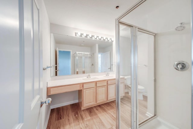 bathroom featuring hardwood / wood-style floors, vanity, toilet, and a shower with shower door