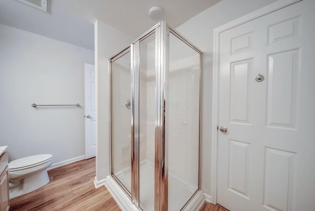 bathroom featuring hardwood / wood-style floors, vanity, toilet, and walk in shower