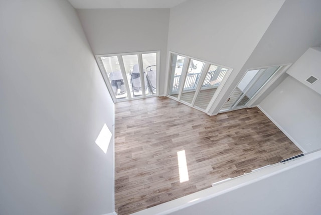 unfurnished living room with high vaulted ceiling and light hardwood / wood-style flooring