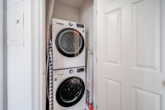 laundry room with electric panel and stacked washing maching and dryer