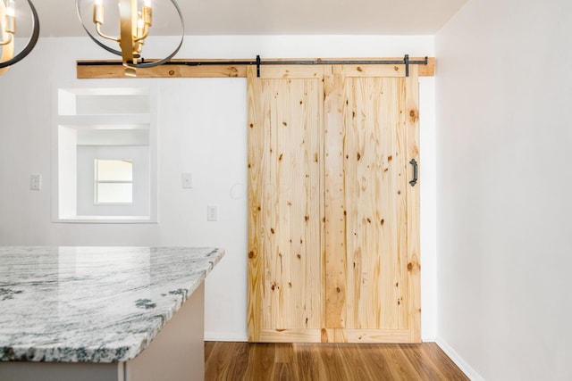 interior space featuring light stone countertops, a barn door, dark hardwood / wood-style floors, and a chandelier