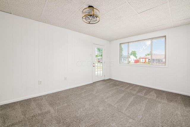 spare room featuring carpet flooring, a drop ceiling, and a wealth of natural light