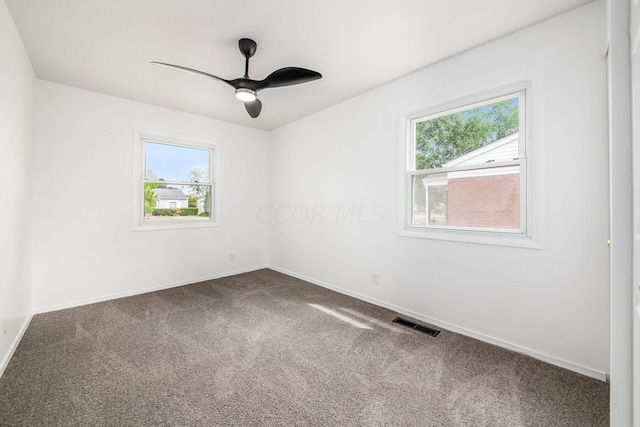 carpeted empty room with a wealth of natural light and ceiling fan