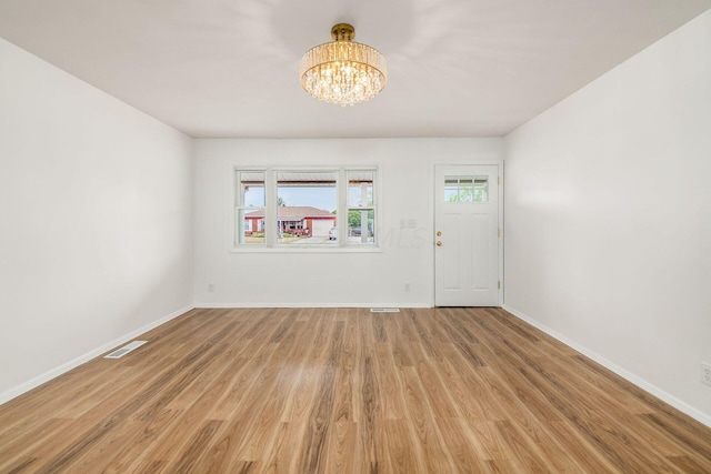 entrance foyer featuring light hardwood / wood-style floors and a notable chandelier