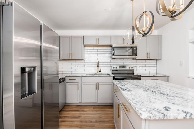 kitchen featuring an inviting chandelier, sink, gray cabinets, light wood-type flooring, and stainless steel appliances