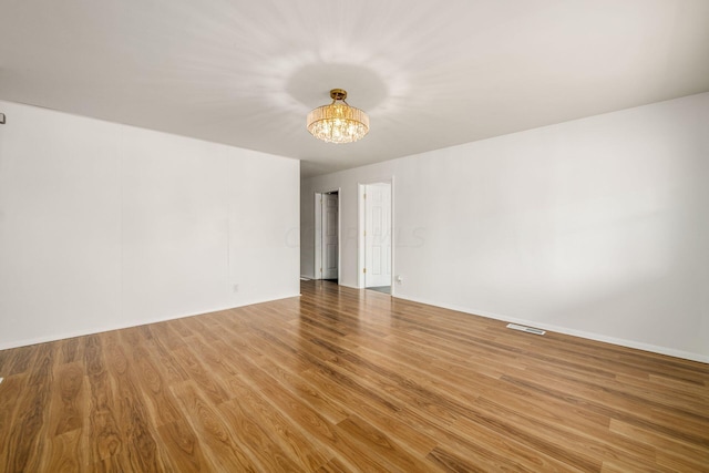 unfurnished room with wood-type flooring and a chandelier