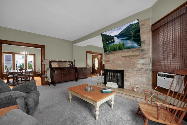 living room featuring cooling unit, a stone fireplace, carpet floors, and a chandelier