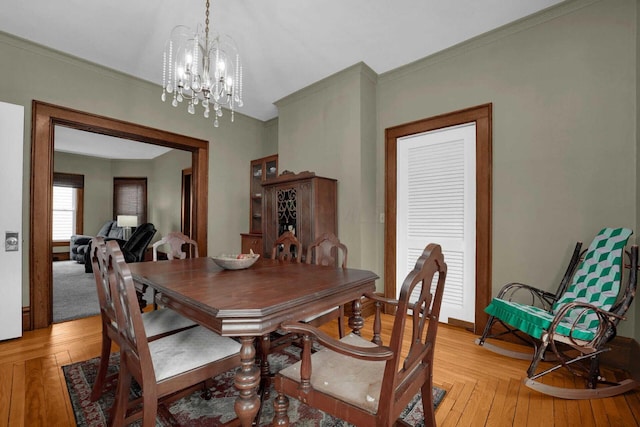 dining area with light hardwood / wood-style floors, crown molding, and an inviting chandelier