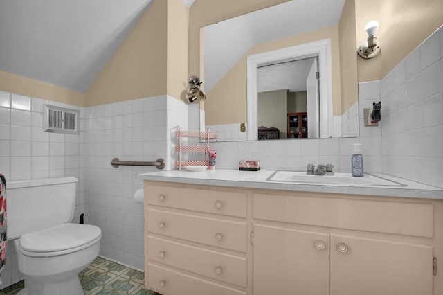 bathroom with tile patterned floors, vanity, tile walls, toilet, and lofted ceiling