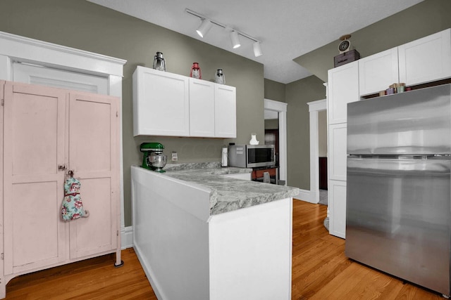 kitchen featuring light stone countertops, appliances with stainless steel finishes, track lighting, light hardwood / wood-style flooring, and white cabinets