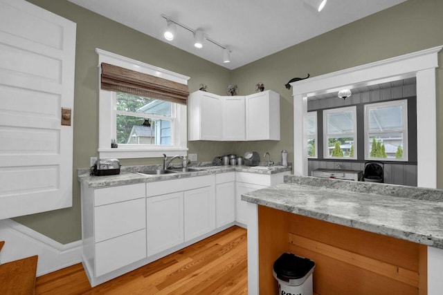 kitchen featuring white cabinets, light hardwood / wood-style floors, light stone countertops, and sink