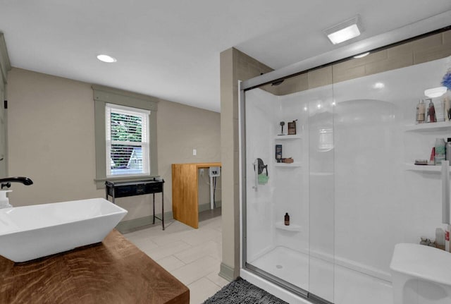 bathroom with tile patterned floors, sink, a shower with shower door, and toilet