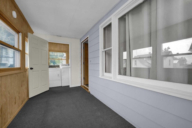 corridor with wood walls, dark carpet, and washing machine and clothes dryer