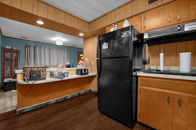 kitchen with black refrigerator, dark hardwood / wood-style flooring, and crown molding