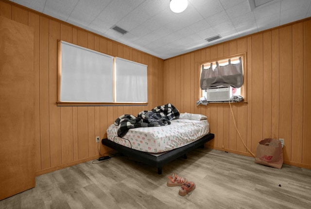 bedroom with wood walls, cooling unit, and light wood-type flooring