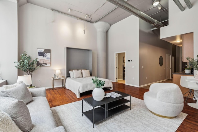 bedroom with wood-type flooring, rail lighting, and a high ceiling