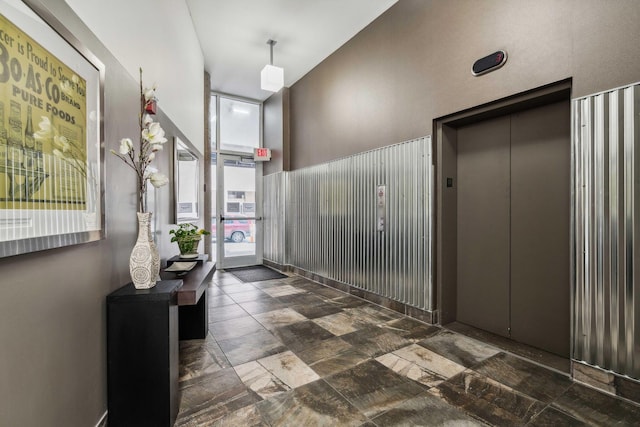 hallway with a towering ceiling and elevator