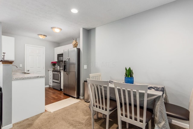 carpeted dining area featuring sink and a textured ceiling