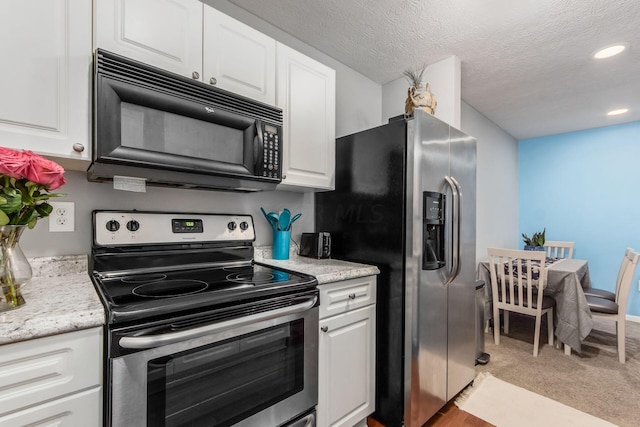 kitchen with light stone counters, light colored carpet, a textured ceiling, white cabinets, and appliances with stainless steel finishes