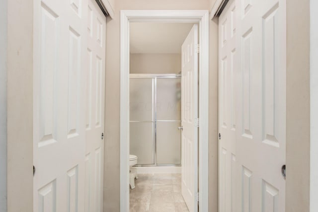 bathroom featuring a shower with door and toilet